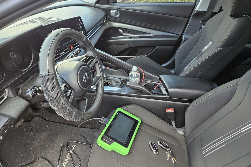Key programming equipment plugged in on the driver's seat of a Hyundai while a new key is coded to the car.
